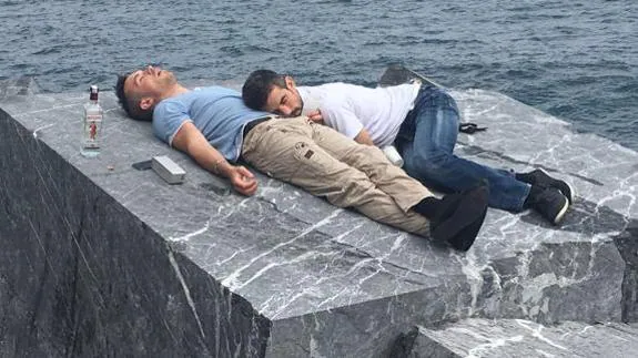 Los dos jóvenes dormidos sobre la roca en el mar.