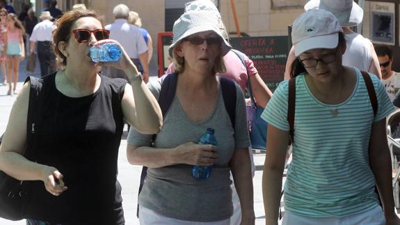 Tres mujeres se protegen del sol y del calor, este domingo, en Segovia. 