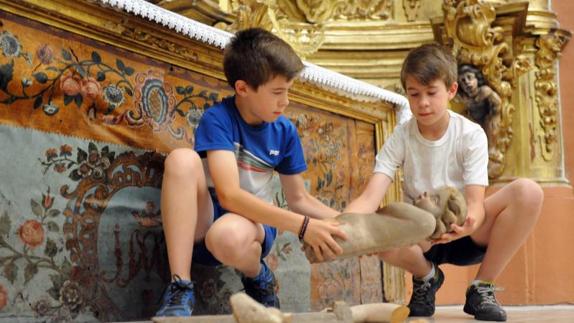 Dos monaguillos retiran del suelo uno de los angelotes caídos. 