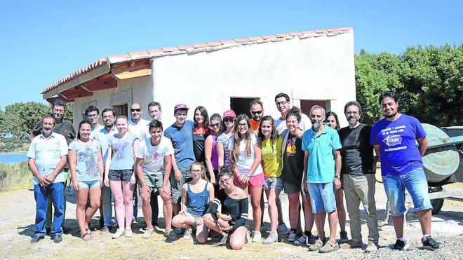 Los participantes del campo de trabajo internacional y los responsables de la Junta y del Ayuntamiento posan frente al edificio donde están trabajando.