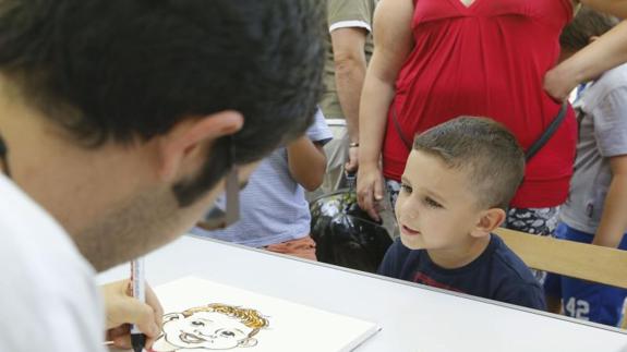 Un caricaturista dibuja a un niño en la Acera de Recoletos.