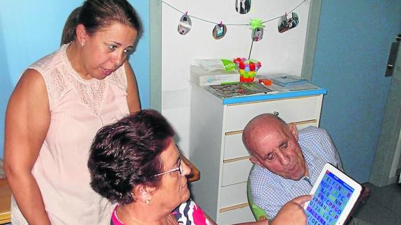 Begoña Losada, cuidadora de AFA, observa a una paciente mientras realiza ejercicios con tablet. 