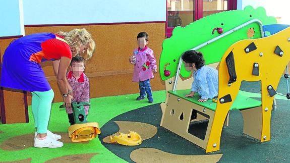 Varios niños y una profesora en una zona de juegos del centro la Senda. 