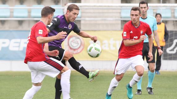 Diego Torres controla el balón ante dos hombres del Osasuna B. 