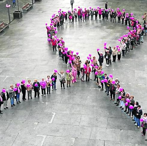Un centenar de personas portando globos de color rosa formaron en la tarde de ayer un gran lazo humano en la Plaza de Guijuelo. 