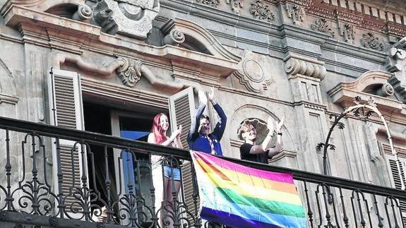 Miembros del movimiento LGTB+ despliegan su bandera en uno de los balcones del Ayuntamiento.