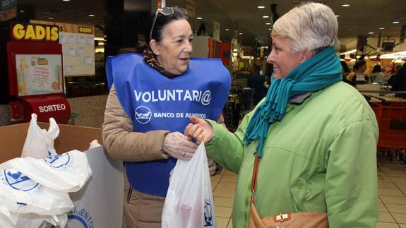 Una voluntaria recoge los productos que entrega una mujer.