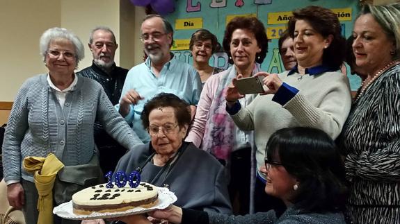 Marina Rubio sujeta la tarta en su cien cumpleaños, junto a sus familiares. 