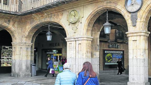 Paseantes en la Plaza Mayor bajo el medallón. 