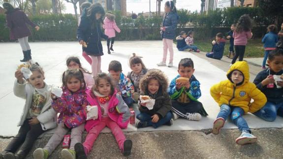 Algunos de los escolares más jóvenes muestras su bocadillo en el recreo. 