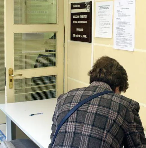 Una mujer cumplimenta un formulario en la entrada a la sección de Tributos del Ayuntamiento de Segovia. 