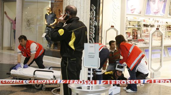 El guardia de seguridad que recibió un disparo en el glúteo es atendido en el suelo mientras que su compañero, con sangre en la cabeza, hace uso de un 'walkie talkie'.