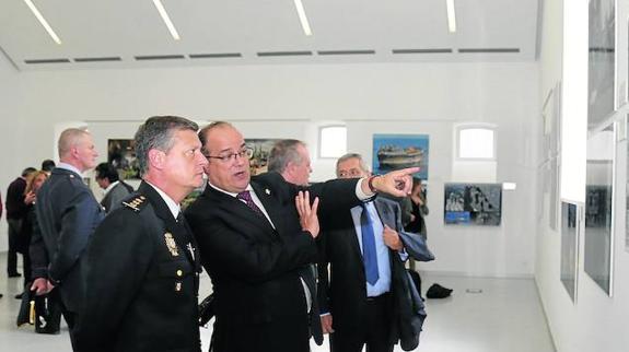 El subdelegado del Gobierno, Luis Miguel Cárcel, explica al comisario jefe, Jesús del Amo, una imagen de la exposición. 