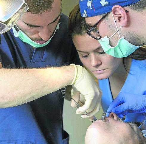 Estudiantes en prácticas observan la boca de una paciente.