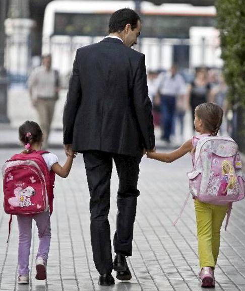 Un padre lleva a sus hijos al colegio