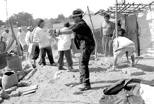 El policía local palentino toma nota de las entregas. En la otra imagen, los peruanos esperan el reparto de material desde un camión.