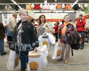 María Cruz, Carmen y Encarna miran un expositor, ya cargadas con varias bolsas.