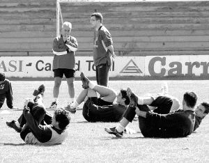 Josu Ortuondo charla con el fisioterapeuta del Palencia mientras los jugadores de la plantilla morada hacen abdominales. / J. RUIZ