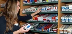 Una joven coge varias cajetillas de cigarrillos en las estanteterías de un estanco. / EL NORTE