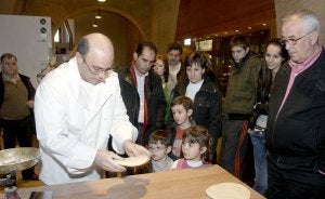 Los visitantes contemplan cómo se amasa el pan. ::                             EFE