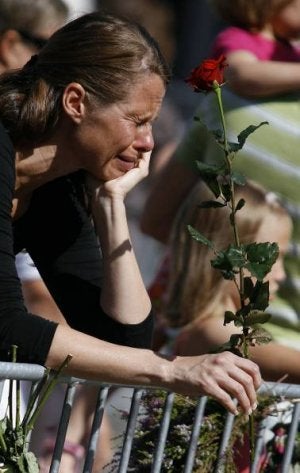 Una mujer homenajea a las víctimas. Arriba, Utoya, donde murieron 69 personas. ::
REUTERS