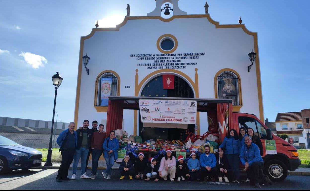 Colaboradores de La Merced se fotografían junto a los alimentos en su casa de hermandad. 