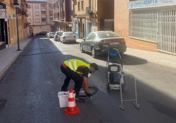 Un operario manipula una tapa de registro en una calle de la ciudad