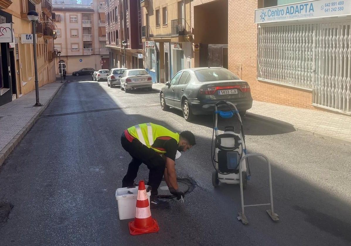 Un operario manipula una tapa de registro en una calle de la ciudad