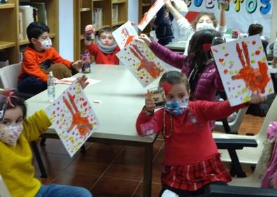 Imagen secundaria 1 - Arriba, Esther Cordero, responsable de la biblioteca arroyana, contando un cuento. Debajo, los pequeños en una sesión de dibujo tras la lectura. 
