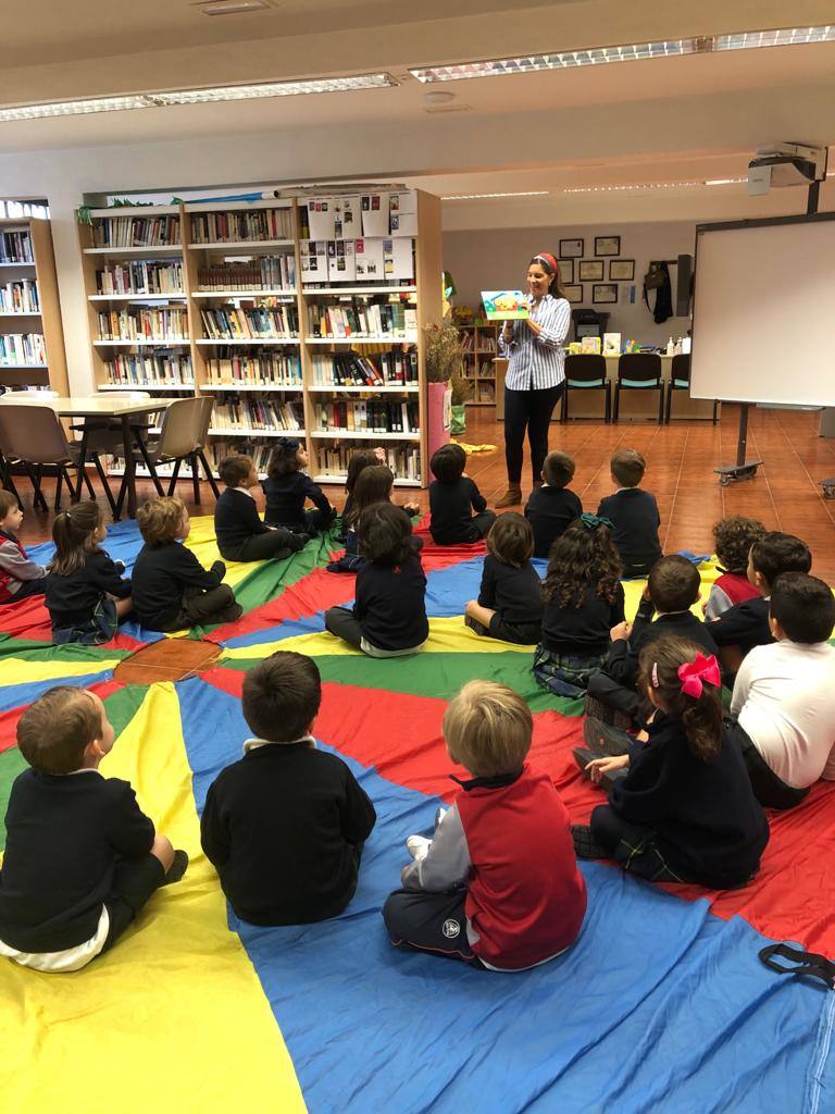 Imagen principal - Esther Cordero, responsable de la biblioteca arroyana, enseñando diferentes libros a los niños. 