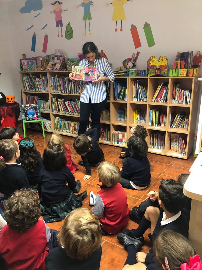 Imagen secundaria 1 - Esther Cordero, responsable de la biblioteca arroyana, enseñando diferentes libros a los niños. 