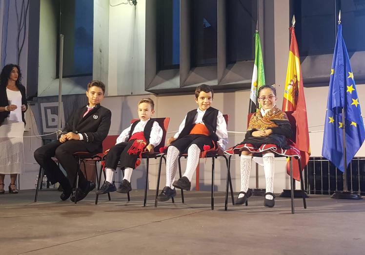 Imagen principal - Niños que portaron las banderas, antes del acto, sentados en el escenario.