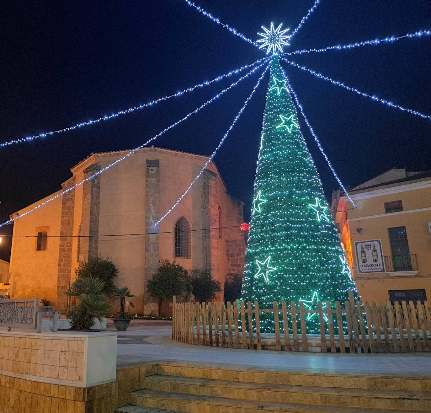 Campanario invita estos días a dar un paseo por sus calles contemplando las luces de colores y todos los motivos que marcan el camino. Pero, si hay algo que llama la atención del alumbrado navideño campanariense, es esa bonita postal desde la iglesia hasta la Plaza de España, donde espera un gran árbol de Navidad rodeado de guirnaldas de luces blancas. 