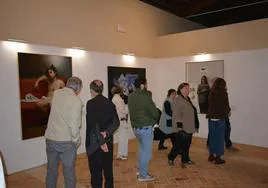 Varias personas contemplando las obras expuestas durante la inauguración.