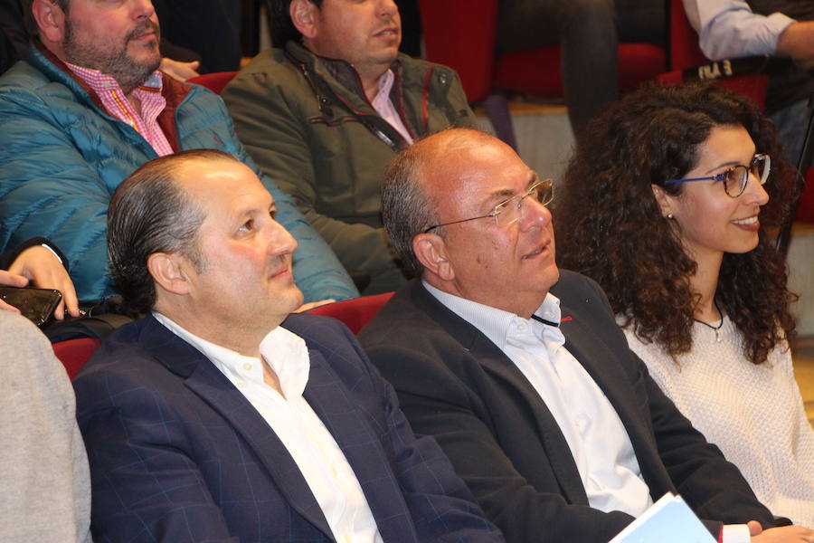 Pedro Romero junto a José Antonio Monago en primera fila de un salón de actos completo de público.