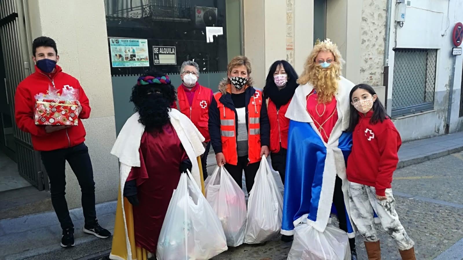 Voluntarios de Cruz Roja y los Reyes Magos, esta mañana,durante la entrega de los regalos. 