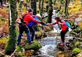 Dos senderistas ayudando a cruzar uno de los arroyos a otra participante.