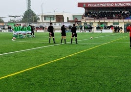 Los dos equipos, el trió arbitral y los espectadores durante el minuto de silencio.
