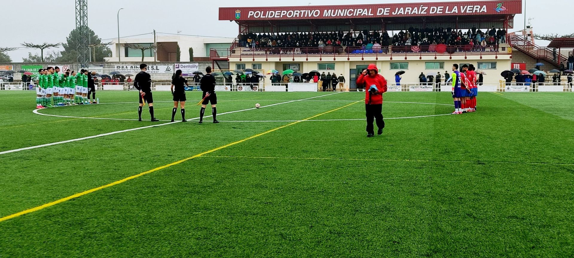 Los dos equipos, el trió arbitral y los espectadores durante el minuto de silencio.