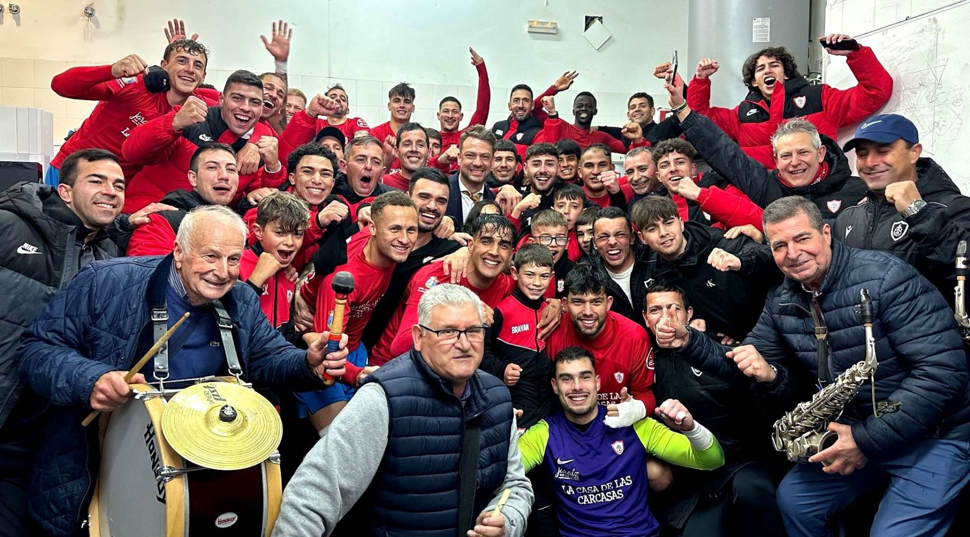 Jugadadores, técnicos, aficionados y la charagan La Alegría celebran la victoria al término de partido.