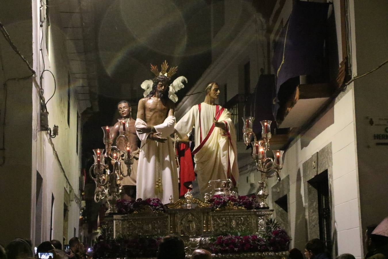 La vista al cielo se convertía, ayer, en una de las prácticas más repetida por los jerezanos. La lluvia amenazaba con marcar un antes y después en la Semana Santa jerezana 2019, Fiesta de Interés Turístico Nacional, e impedir la salida de la Cofradía del Señor 'Ecce-Homo', protagonista del Miércoles Santo. Una leve llovizna que, comenzaría a principio de la tarde, se convirtió en persistente a medida que pasaban las horas. Razón por la que la Cofradía decidió retrasar su hora de salida hasta pasadas las 21:30 horas, cuando la puerta del Perdón de San Miguel Arcángel se abría para iniciar el desfile procesional. Un desfile procesional que se vio interrumpido, de nuevo, por la lluvia, obligando al Señor 'Ecce-Homo' y Nuestra Señora de los Desamparados a regresar al templo. 