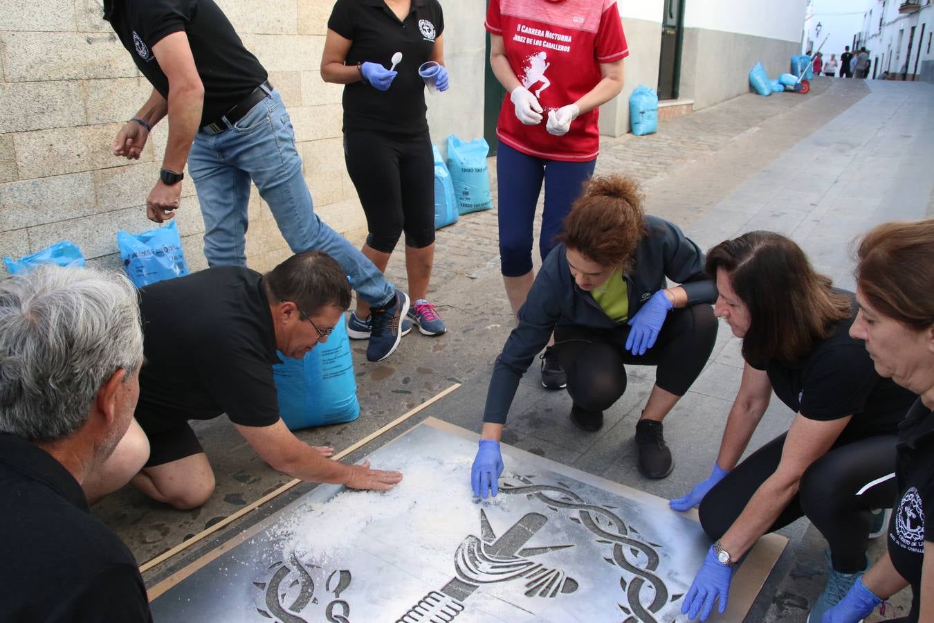 Las alfombras de sal embellecen y llenan de color, hoy, las calles de Jerez de los Caballeros con motivo de la festividad del Corpus Christi. Desde primera hora de la mañana, miembros de las cofradías y hermandades, Cáritas, grupos de catequesis, familias de los niños que han hecho este año la Primera Comunión, miembros de la Asociación de costaleros y costaleras de la Semana Santa jerezana, Ayuntamiento y vecinos han cubierto las principales calles del municipio con 6.250 kilos de sal teñida, plenas de color. A continuación, han disfrutado de una jornada de convivencia en la Casa de la Iglesia 'Cecilia de Arteaga'.