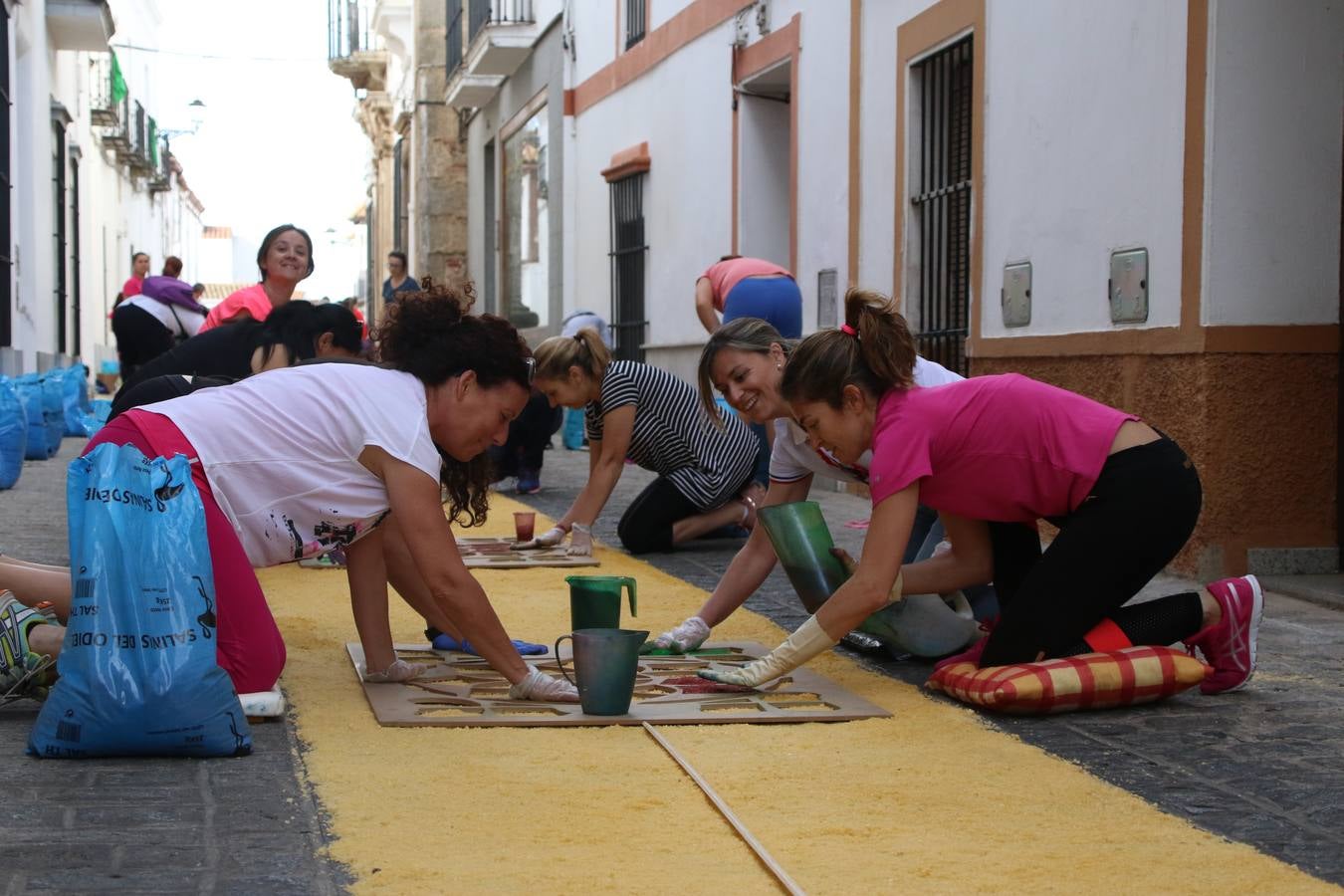 Las alfombras de sal embellecen y llenan de color, hoy, las calles de Jerez de los Caballeros con motivo de la festividad del Corpus Christi. Desde primera hora de la mañana, miembros de las cofradías y hermandades, Cáritas, grupos de catequesis, familias de los niños que han hecho este año la Primera Comunión, miembros de la Asociación de costaleros y costaleras de la Semana Santa jerezana, Ayuntamiento y vecinos han cubierto las principales calles del municipio con 6.250 kilos de sal teñida, plenas de color. A continuación, han disfrutado de una jornada de convivencia en la Casa de la Iglesia 'Cecilia de Arteaga'.