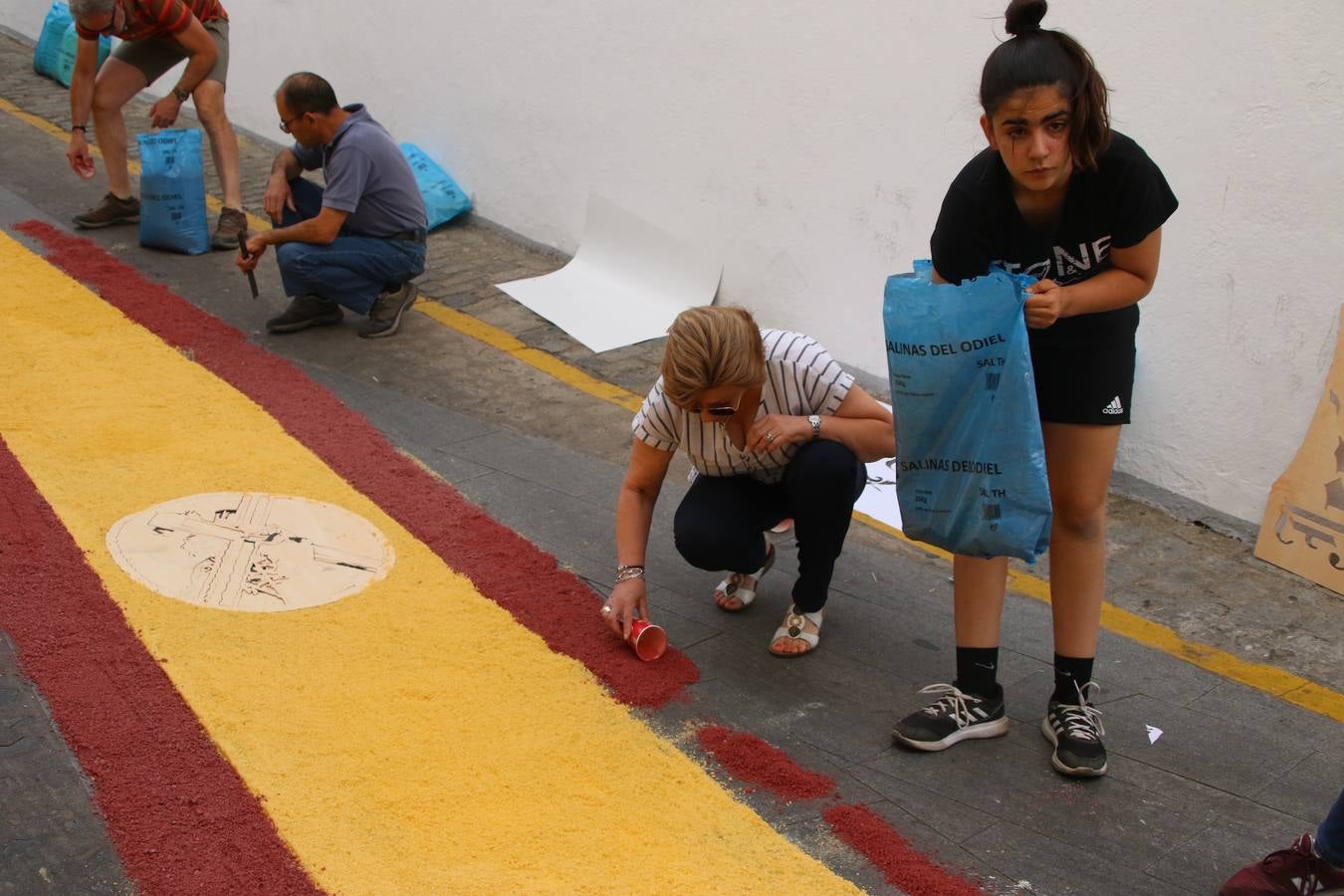 Las alfombras de sal embellecen y llenan de color, hoy, las calles de Jerez de los Caballeros con motivo de la festividad del Corpus Christi. Desde primera hora de la mañana, miembros de las cofradías y hermandades, Cáritas, grupos de catequesis, familias de los niños que han hecho este año la Primera Comunión, miembros de la Asociación de costaleros y costaleras de la Semana Santa jerezana, Ayuntamiento y vecinos han cubierto las principales calles del municipio con 6.250 kilos de sal teñida, plenas de color. A continuación, han disfrutado de una jornada de convivencia en la Casa de la Iglesia 'Cecilia de Arteaga'.