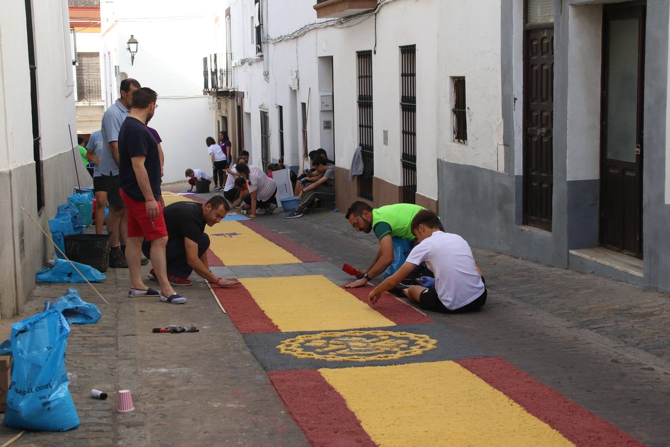 Las alfombras de sal embellecen y llenan de color, hoy, las calles de Jerez de los Caballeros con motivo de la festividad del Corpus Christi. Desde primera hora de la mañana, miembros de las cofradías y hermandades, Cáritas, grupos de catequesis, familias de los niños que han hecho este año la Primera Comunión, miembros de la Asociación de costaleros y costaleras de la Semana Santa jerezana, Ayuntamiento y vecinos han cubierto las principales calles del municipio con 6.250 kilos de sal teñida, plenas de color. A continuación, han disfrutado de una jornada de convivencia en la Casa de la Iglesia 'Cecilia de Arteaga'.