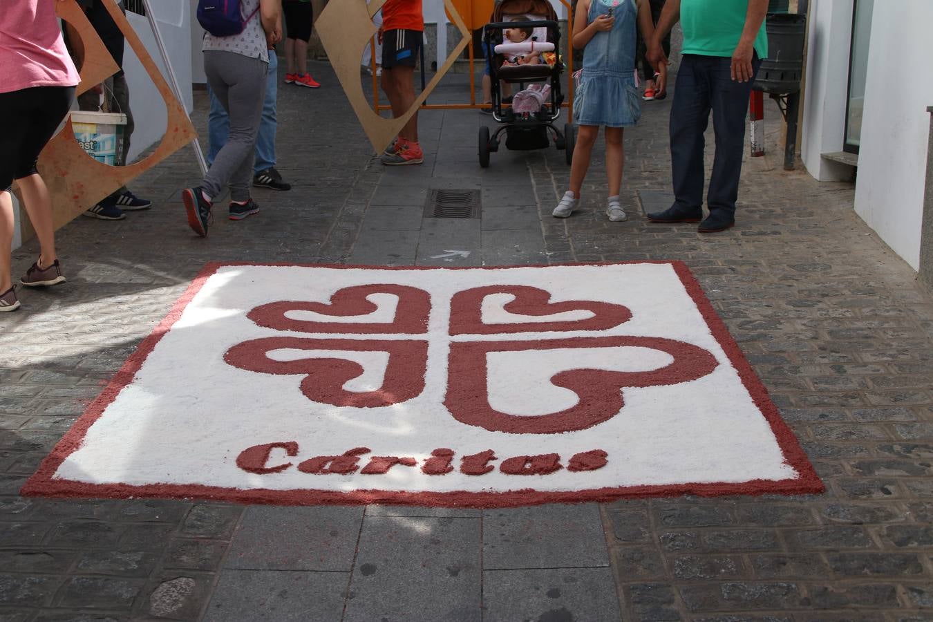 Las alfombras de sal embellecen y llenan de color, hoy, las calles de Jerez de los Caballeros con motivo de la festividad del Corpus Christi. Desde primera hora de la mañana, miembros de las cofradías y hermandades, Cáritas, grupos de catequesis, familias de los niños que han hecho este año la Primera Comunión, miembros de la Asociación de costaleros y costaleras de la Semana Santa jerezana, Ayuntamiento y vecinos han cubierto las principales calles del municipio con 6.250 kilos de sal teñida, plenas de color. A continuación, han disfrutado de una jornada de convivencia en la Casa de la Iglesia 'Cecilia de Arteaga'.
