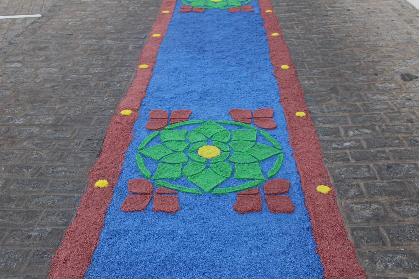 Las alfombras de sal embellecen y llenan de color, hoy, las calles de Jerez de los Caballeros con motivo de la festividad del Corpus Christi. Desde primera hora de la mañana, miembros de las cofradías y hermandades, Cáritas, grupos de catequesis, familias de los niños que han hecho este año la Primera Comunión, miembros de la Asociación de costaleros y costaleras de la Semana Santa jerezana, Ayuntamiento y vecinos han cubierto las principales calles del municipio con 6.250 kilos de sal teñida, plenas de color. A continuación, han disfrutado de una jornada de convivencia en la Casa de la Iglesia 'Cecilia de Arteaga'.