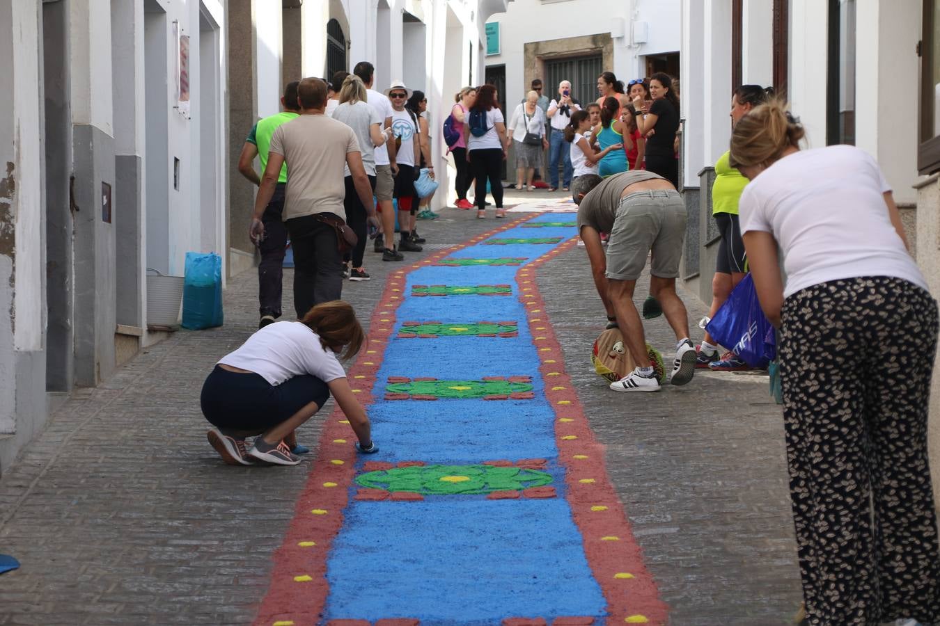 Las alfombras de sal embellecen y llenan de color, hoy, las calles de Jerez de los Caballeros con motivo de la festividad del Corpus Christi. Desde primera hora de la mañana, miembros de las cofradías y hermandades, Cáritas, grupos de catequesis, familias de los niños que han hecho este año la Primera Comunión, miembros de la Asociación de costaleros y costaleras de la Semana Santa jerezana, Ayuntamiento y vecinos han cubierto las principales calles del municipio con 6.250 kilos de sal teñida, plenas de color. A continuación, han disfrutado de una jornada de convivencia en la Casa de la Iglesia 'Cecilia de Arteaga'.