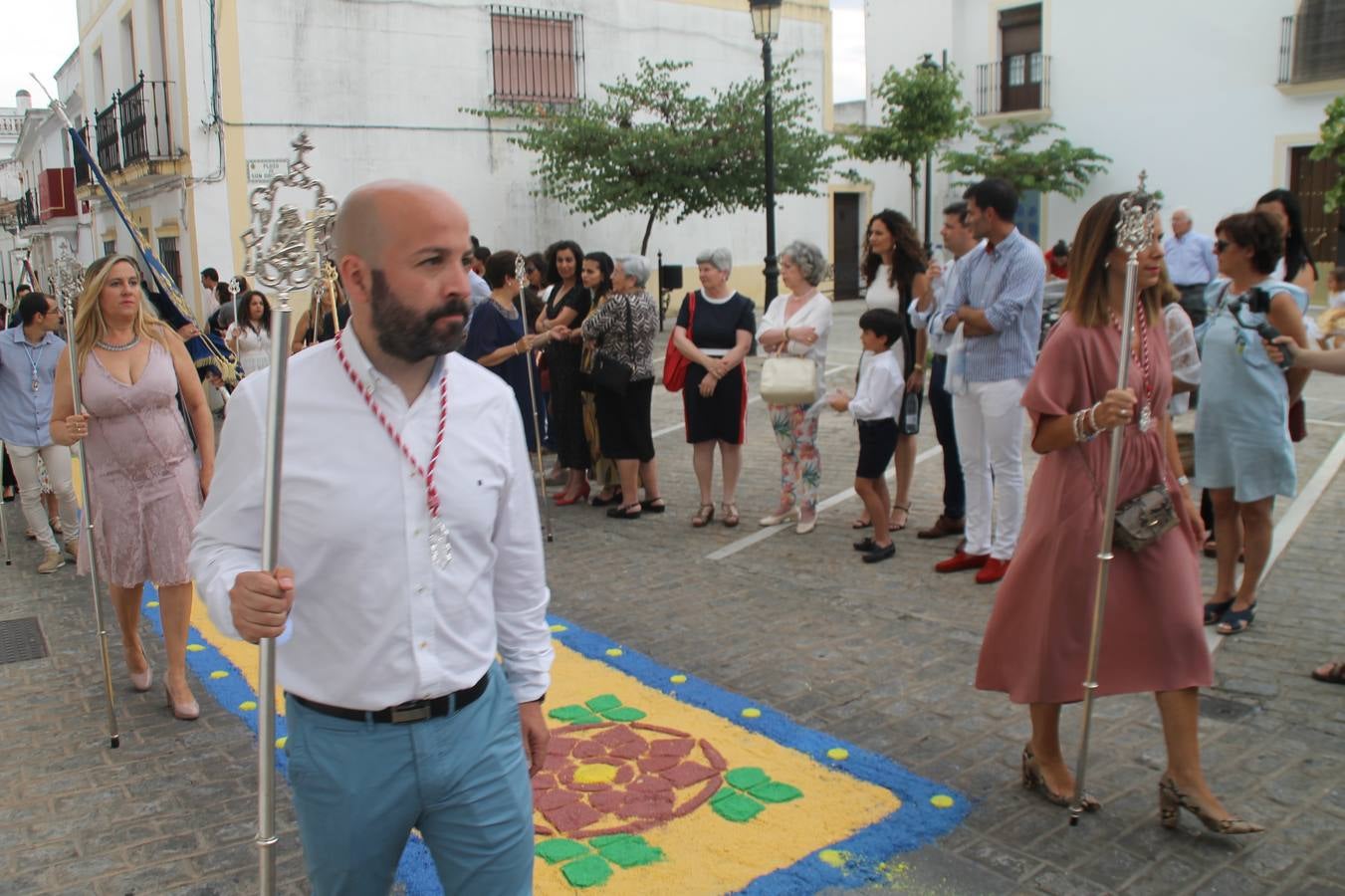 Jerez de los Caballeros celebró ayer la festividad del Corpus Christi en medio de un ambiente de solemnidad y convivencia del que fueron partícipes cientos de personas.La iglesia visigoda de Santa María de la Encarnación, llena de fieles, acogió la celebración de la Eucaristía que dió paso a la procesión acompañando la Santa Custodia en el magnífico templete de la iglesia de San Miguel, sobre las andas de la Virgen de Aguasantas y portada por costaleros y costaleras de la recién Asociación creada en esta ciudad. El párroco, Antonio María Rejano, destacó la significación de esta procesión, lamás grande, dijo, «porque Jesús sale a nuestras vidas, a nuestro encuentro y nosotros le acompañamos». Al término de la misa, incidió en el agradecimiento a todas las personas que han participado para hacer posible su desarrollo, trabajando desde la jornada del sábado en la elaboración de las preciosas alfombras de sal teñida de colores, que lucieron en las calles del centro de Jerez. El agradecimiento fue especial para los padres y madres de los niños y niñas que han hecho la Primera Comunión, para éstos mismos, también para catequistas, Cofradías y Hermandades, la Asociación del costaleros y costaleras de la Semana Santa de Jerez de los Caballeros, Ayuntamiento, Policía Local, grupos y personas de la parroquia.Autoridades civiles en representación del Ayuntamiento, Policía Local y Guardia Civil, acompañaron el desarrollo de la procesión junto a representantes de todas las cofradías y hermandades jerezanas y el protagonismo de los más de 80 niños y niñas que este año han celebrado su Primera Comunión.  A lo largo de todo el recorrido se instalaron distintos altares, también con la colaboración de vecinos y centros como la Residencia de Mayores Hernando de Soto. Los magníficos sones de la Agrupación Musical 'Nuestro Padre Jesús Nazareno' coronaron esta hermosa procesión.