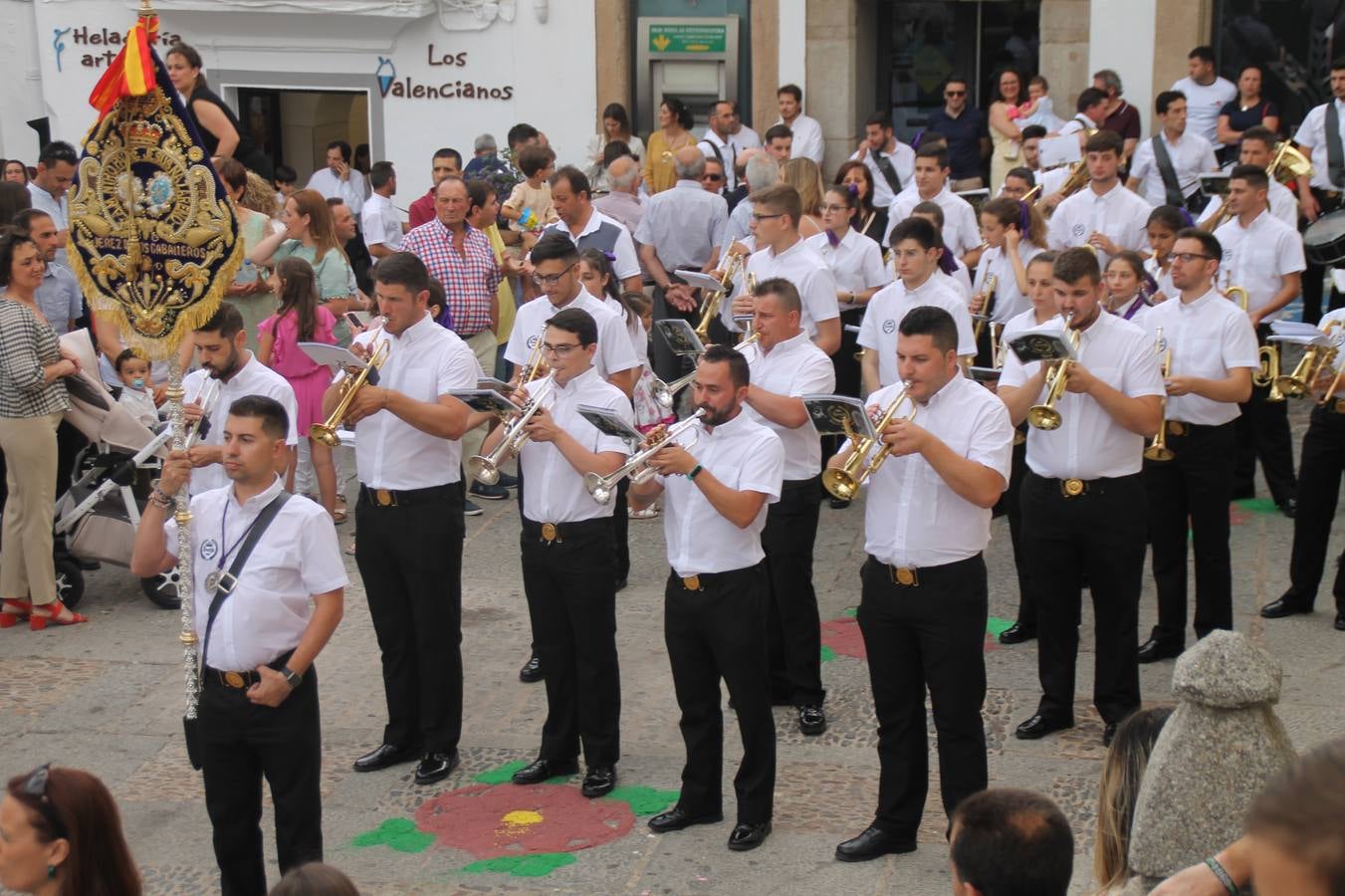 Jerez de los Caballeros celebró ayer la festividad del Corpus Christi en medio de un ambiente de solemnidad y convivencia del que fueron partícipes cientos de personas.La iglesia visigoda de Santa María de la Encarnación, llena de fieles, acogió la celebración de la Eucaristía que dió paso a la procesión acompañando la Santa Custodia en el magnífico templete de la iglesia de San Miguel, sobre las andas de la Virgen de Aguasantas y portada por costaleros y costaleras de la recién Asociación creada en esta ciudad. El párroco, Antonio María Rejano, destacó la significación de esta procesión, lamás grande, dijo, «porque Jesús sale a nuestras vidas, a nuestro encuentro y nosotros le acompañamos». Al término de la misa, incidió en el agradecimiento a todas las personas que han participado para hacer posible su desarrollo, trabajando desde la jornada del sábado en la elaboración de las preciosas alfombras de sal teñida de colores, que lucieron en las calles del centro de Jerez. El agradecimiento fue especial para los padres y madres de los niños y niñas que han hecho la Primera Comunión, para éstos mismos, también para catequistas, Cofradías y Hermandades, la Asociación del costaleros y costaleras de la Semana Santa de Jerez de los Caballeros, Ayuntamiento, Policía Local, grupos y personas de la parroquia.Autoridades civiles en representación del Ayuntamiento, Policía Local y Guardia Civil, acompañaron el desarrollo de la procesión junto a representantes de todas las cofradías y hermandades jerezanas y el protagonismo de los más de 80 niños y niñas que este año han celebrado su Primera Comunión.  A lo largo de todo el recorrido se instalaron distintos altares, también con la colaboración de vecinos y centros como la Residencia de Mayores Hernando de Soto. Los magníficos sones de la Agrupación Musical 'Nuestro Padre Jesús Nazareno' coronaron esta hermosa procesión.